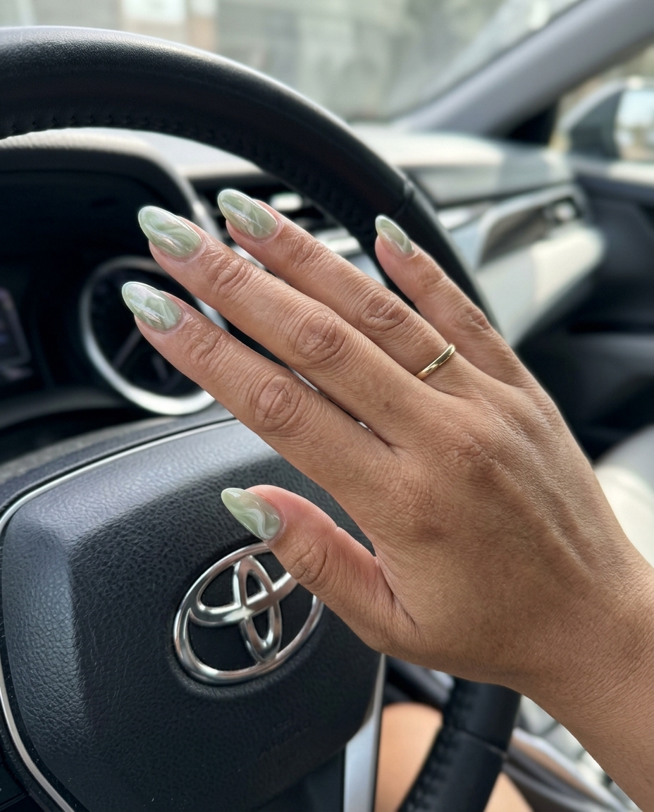 Pretty Green Nails 2026: Glamorous Sage Marble Glazed Donut Pretty green nails 2026: Chic sage green marble nails with a pearlescent glazed donut finish for date nights.