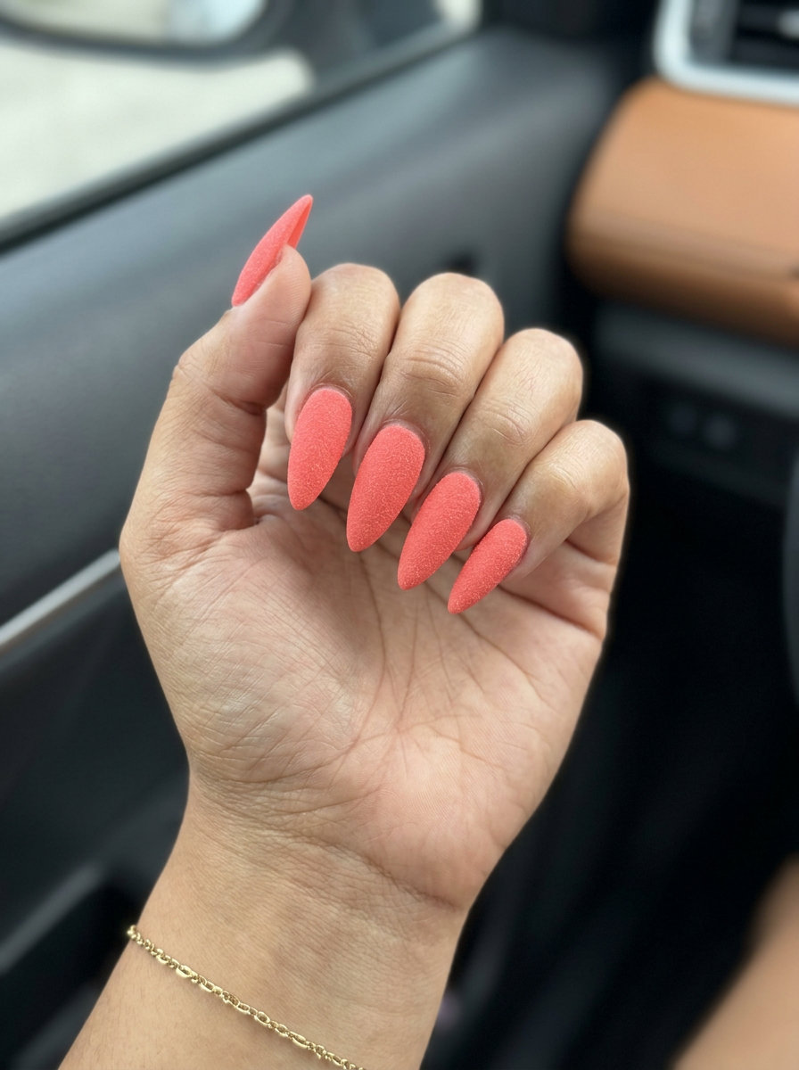 Vibrant coral matte sugar texture stiletto nails for summer festivals 2026. Edgy and playful.