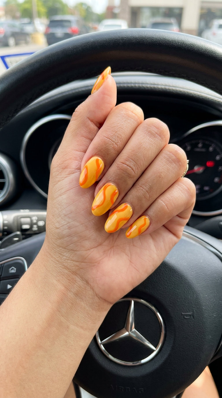 Yellow Summer Nails 2026: Marigold Abstract Marigold yellow nails with abstract orange swirls, ideal for vacation and festivals in summer 2026.