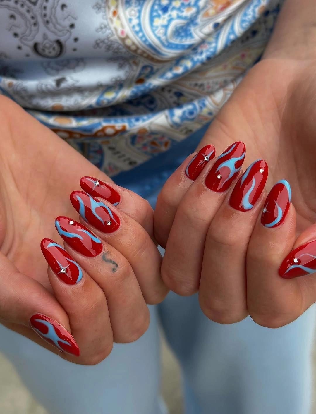 chic fall red nails 2026 Glossy Crimson Swirls With Unexpected Blue Accents
