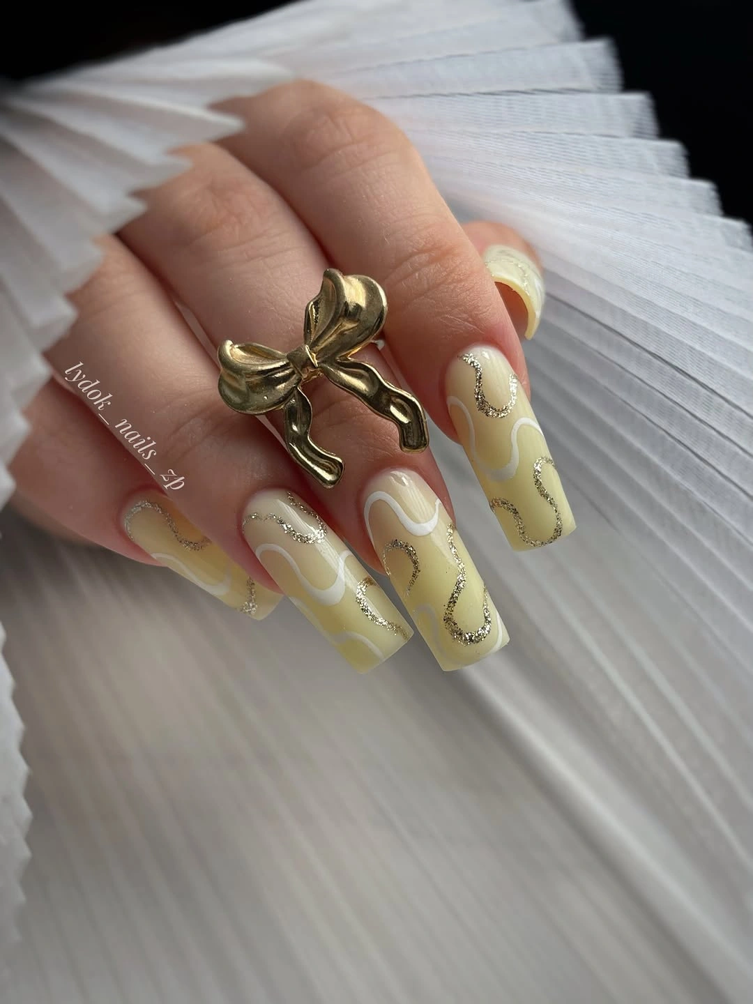 stylish fall gel nails ideas 2026 Creamy Yellow Nails With Gold Swirls And A Bow