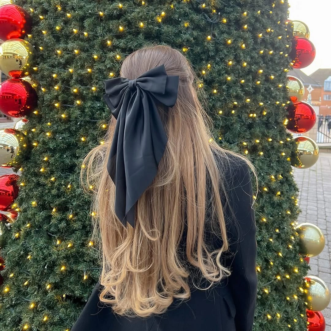 glamorous christmas hairstyles 2026 - Long blonde waves with a navy bow