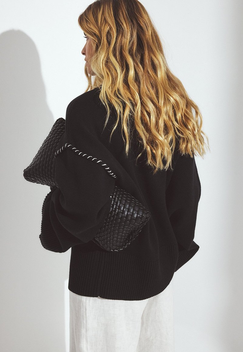 Textural Contrast: Black Knit Sweater with White Linen Pants — Oversized Sweater Outfits