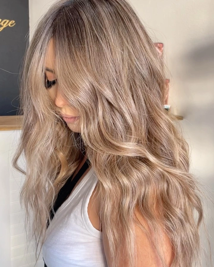 Long wavy beige blonde hair with darker taupe roots Long wavy beige blonde hair with darker taupe roots