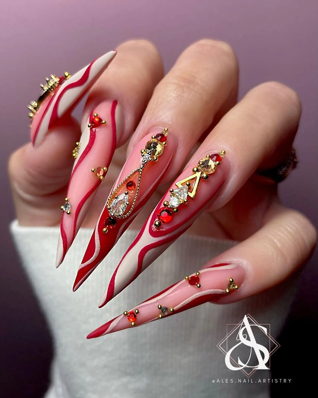 Extra long pointed nails with red swirls gold ornaments and jewel accents Extra long pointed nails with red swirls gold ornaments and jewel accents