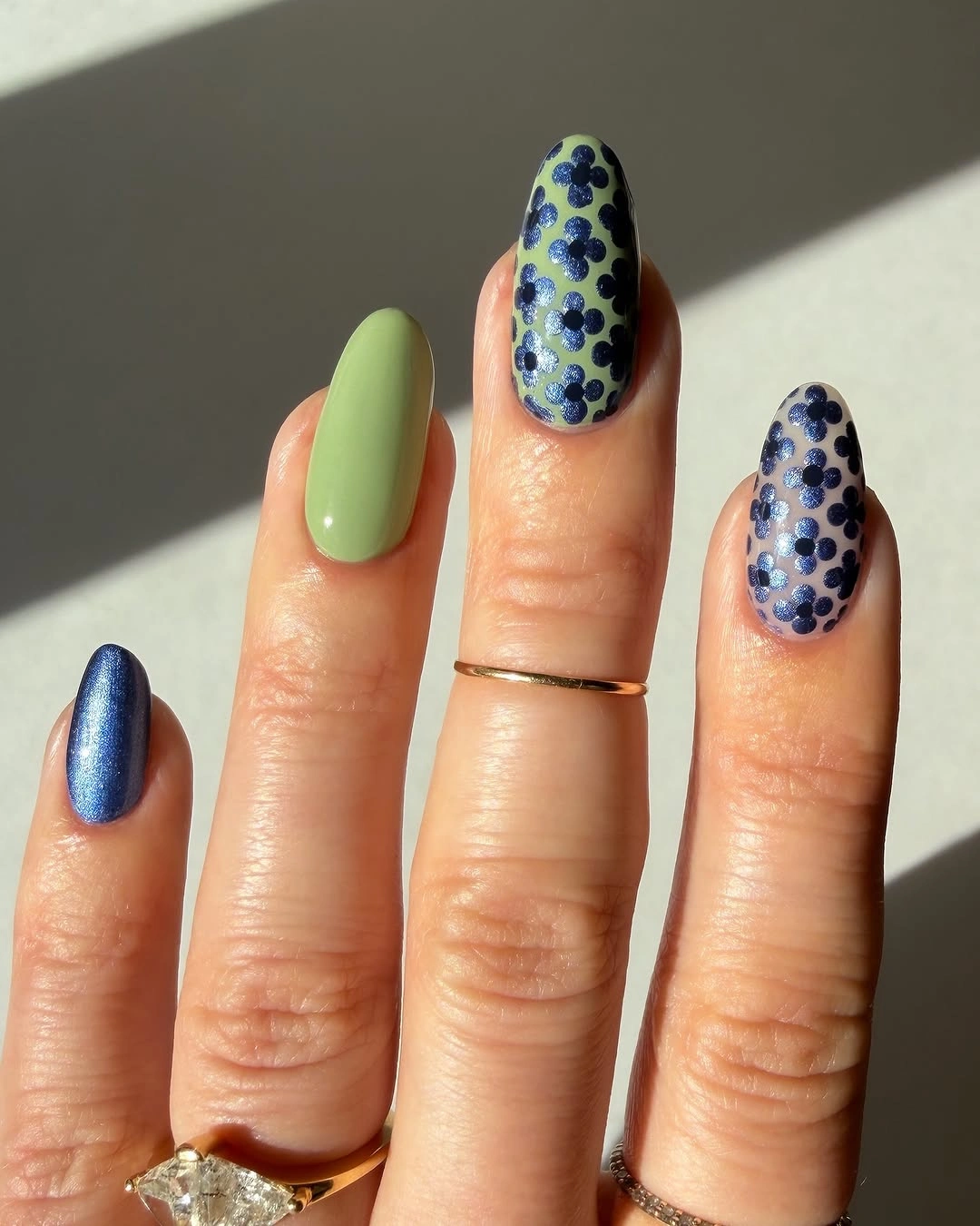 Almond nails with sage green metallic blue and navy flower patterns Almond nails with sage green metallic blue and navy flower patterns