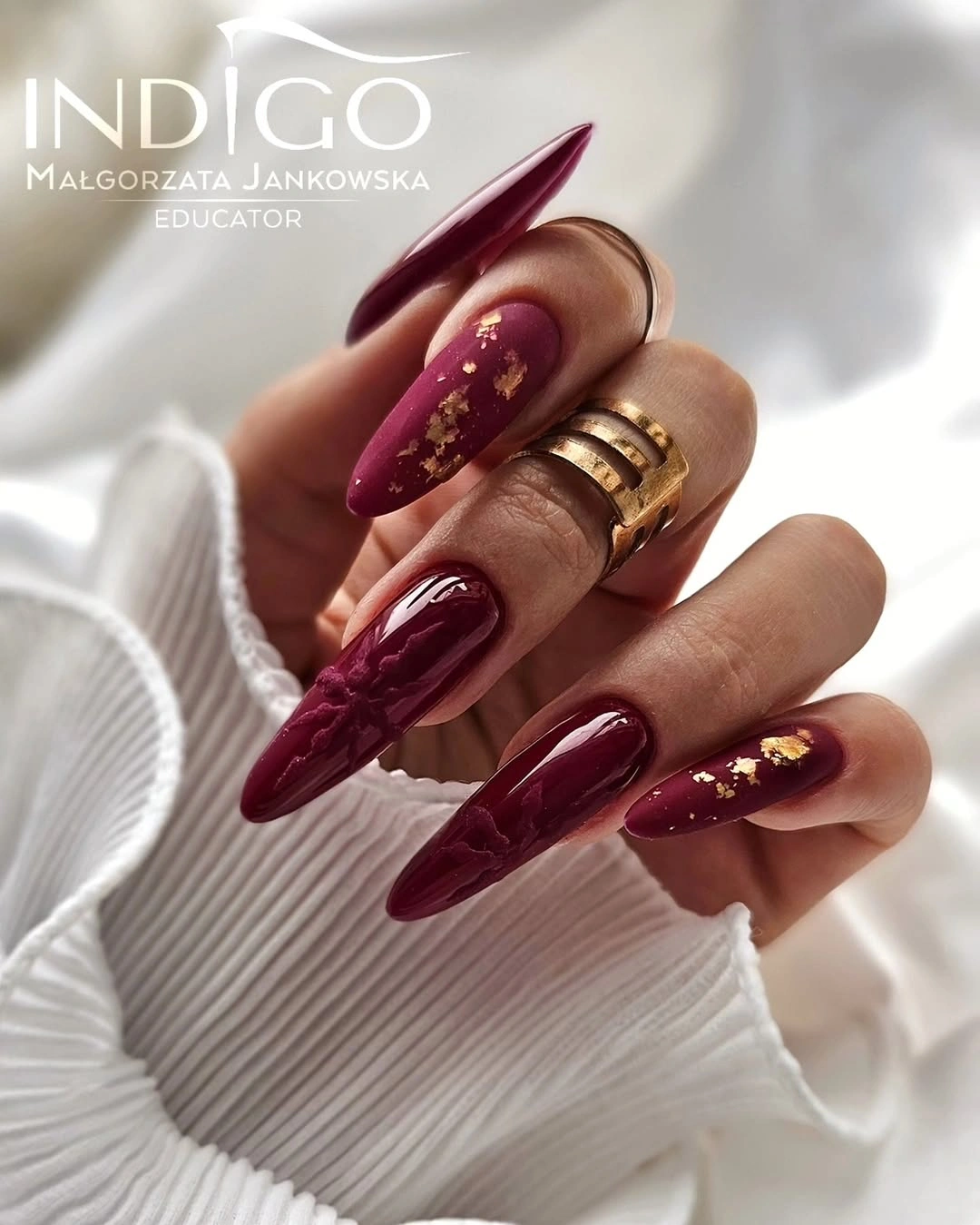 Long burgundy pointed nails with raised-looking swirls and gold flecks Long burgundy pointed nails with raised-looking swirls and gold flecks