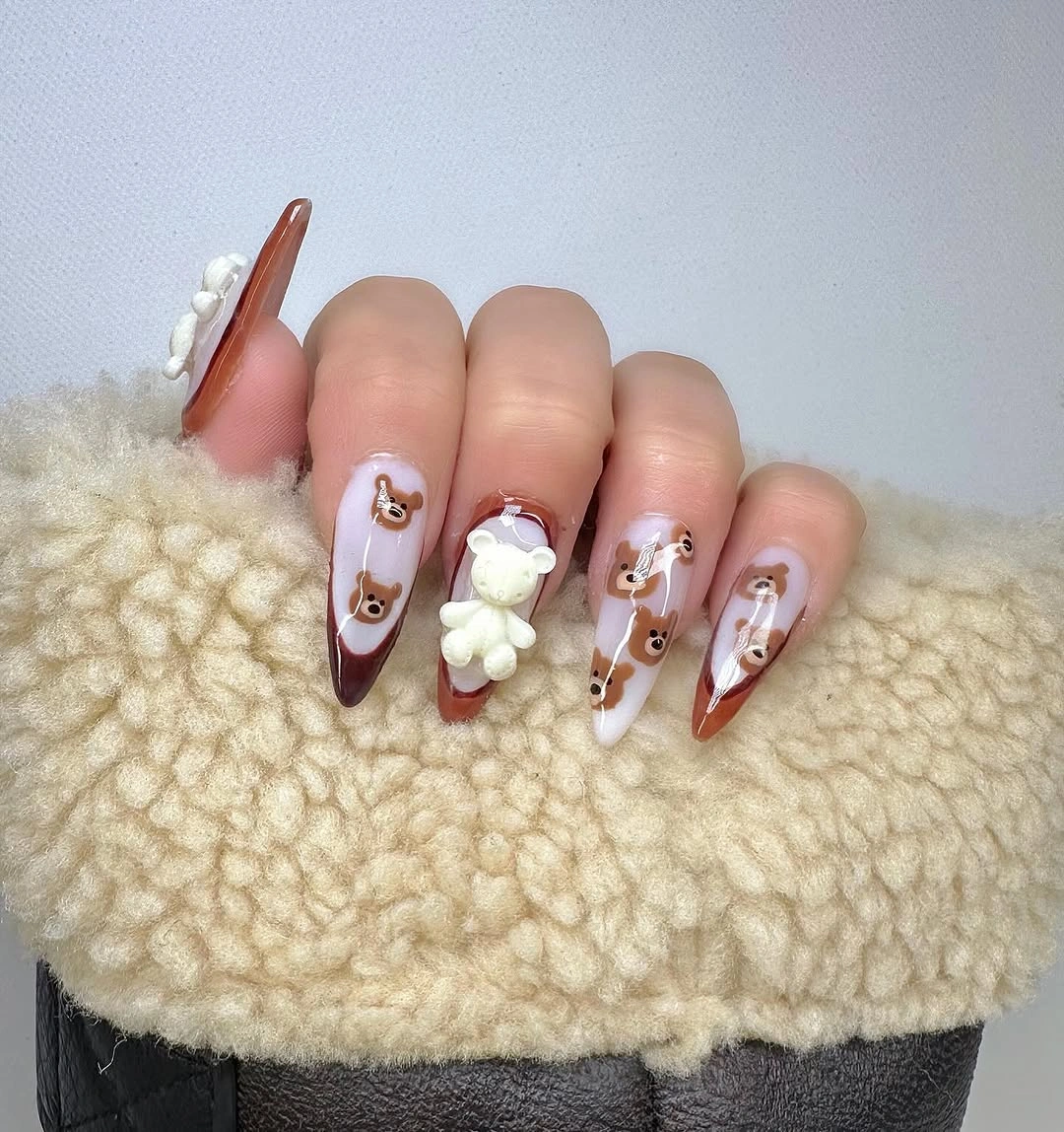 Long pointed nude nails with brown bear faces and a raised white bear Long pointed nude nails with brown bear faces and a raised white bear