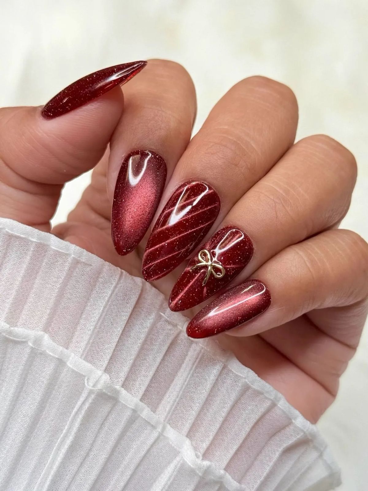 Deep Red Cat-Eye Gold Bow Stilettos Deep Red Cat-Eye Gold Bow Stilettos β Christmas Nails 2026